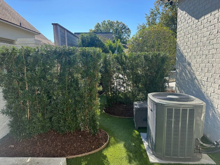 Air conditioning unit by a white brick wall and green hedges—an ideal Example Portfolio photo under a clear blue sky.