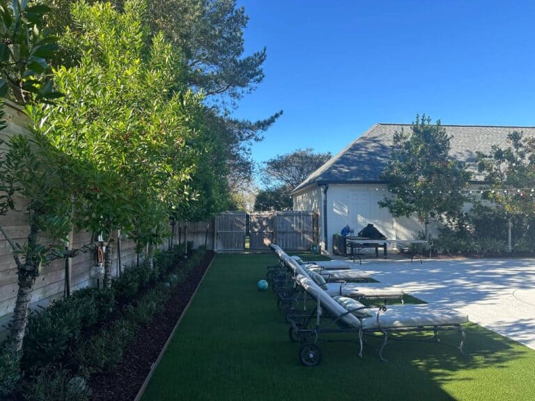 A row of lounge chairs on artificial grass beside a wooden fence—an inviting example portfolio outdoor space.