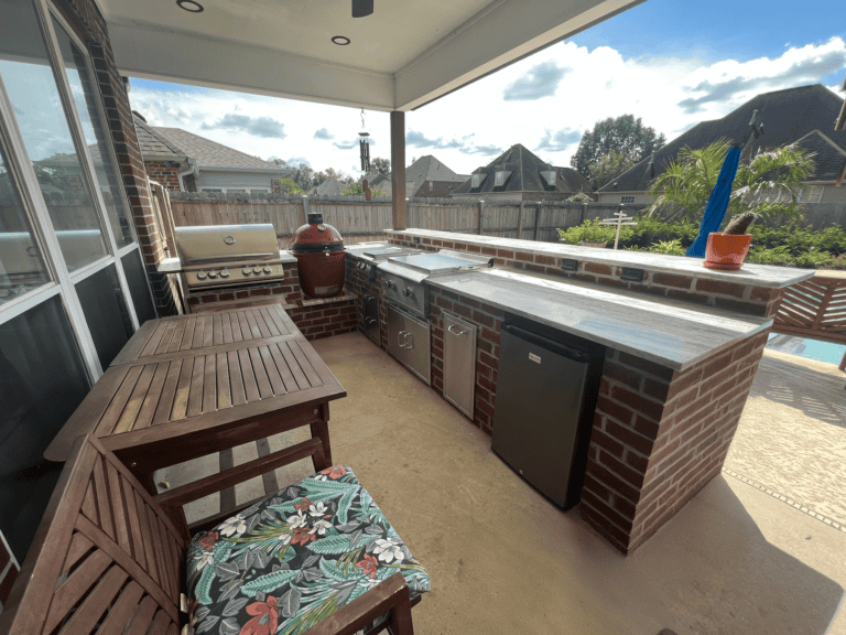 Covered outdoor kitchen creates a Tropical Hideaway with grill, smoker, sink, fridge, counter space, and cozy dining on the patio.